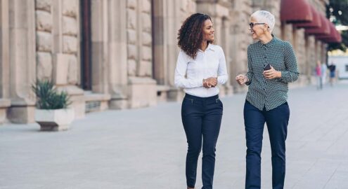 Two educators walking together and talking outdoors in the city
