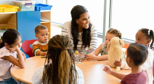Smiling teacher teaching young children